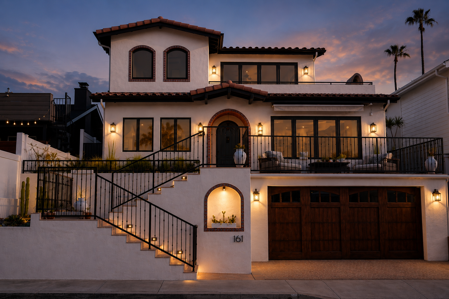 A luxury two-story Haceinda-style villa at dusk, featuring a white stucco exterior, terracotta tile roofs, a black staircase with integrated lighting, a dark wood garage door, and warm outdoor wall sconces against a twilight sky.